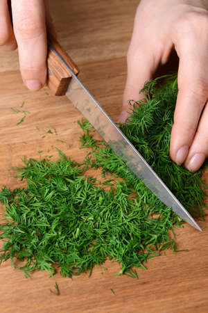 Chopped dill on wooden board close-upの写真素材