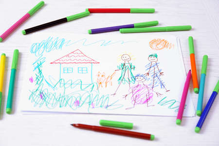 Kids drawing of family and colored pencils on wooden tableの写真素材