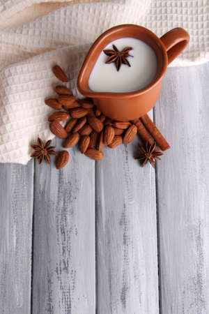 Almond milk in jug with almonds in bowl, on color wooden backgroundの写真素材