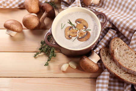 Mushroom soup in pot, on napkin,  on wooden backgroundの写真素材