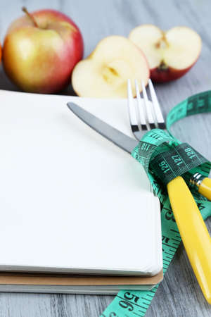 Cutlery tied with measuring tape and notebook with fruits on wooden backgroundの写真素材