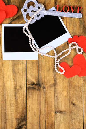 Blank old photos and decorative hearts on color wooden backgroundの写真素材