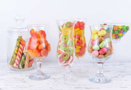 Different colorful fruit candy in glasses on table on light backgroundの写真素材