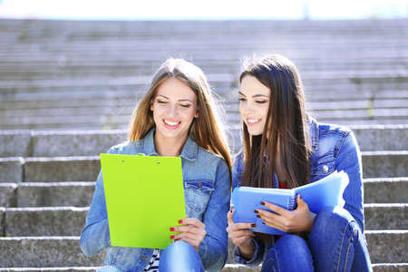 Happy students sitting on stairs in parkの写真素材