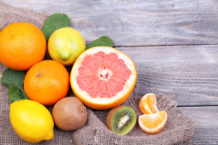 Fresh exotic fruits with green leaves on color wooden backgroundの写真素材