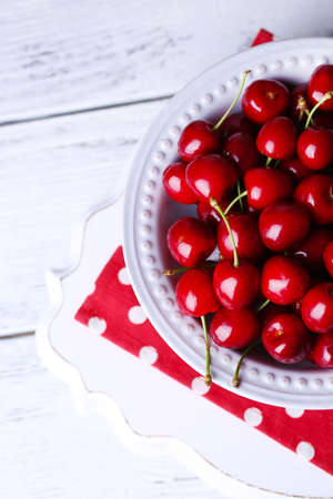 Sweet cherries on plate on wooden backgroundの写真素材