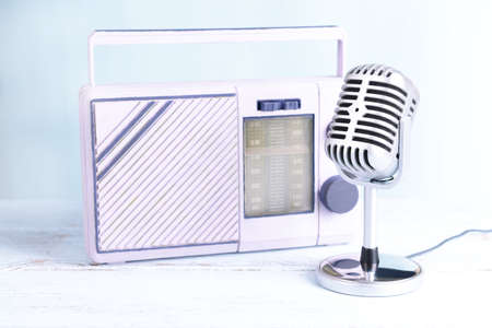 Vintage microphone and radio on table on light blue backgroundの写真素材