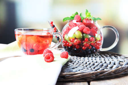 Fruit red tea with wild berries in glass cup, on wooden table, on bright backgroundの写真素材