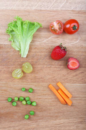 Different slices of vegetables and berries on wooden tableの写真素材