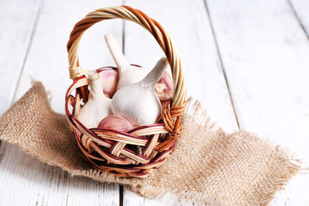 Fresh garlic in wicker basket, on wooden backgroundの写真素材