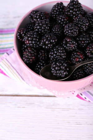 Sweet blackberries in color bowl on wooden backgroundの写真素材