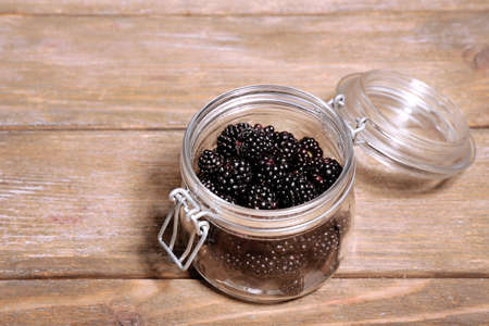 Sweet blackberries in glass jar on wooden backgroundの写真素材