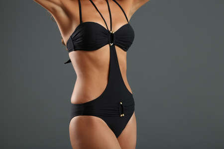 Young woman with slim body in swimsuit on gray backgroundの写真素材