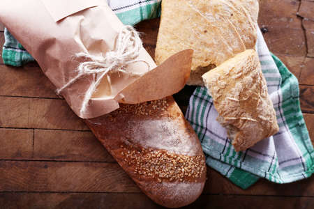Fresh baked bread wrapped in paper, on wooden backgroundの写真素材