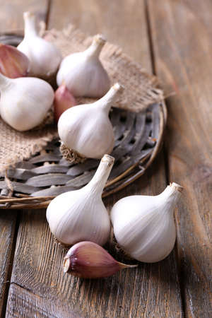 Fresh garlic on wicker mat, on wooden backgroundの写真素材