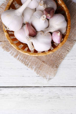 Fresh garlic in wicker basket, on wooden backgroundの写真素材