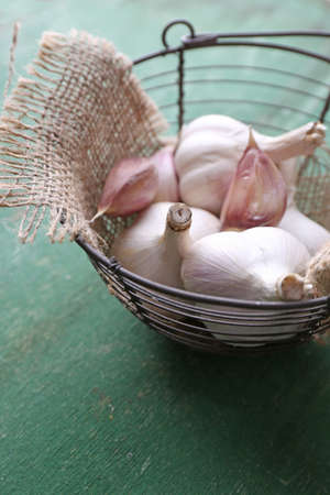 Garlic in basket on color wooden backgroundの写真素材