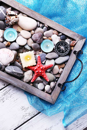 Candles on vintage tray with sea pebbles,starfish and sea shells on wooden backgroundの写真素材