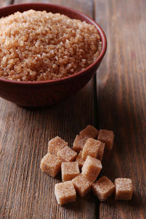 Brown sugar cubes and crystal sugar in bowl on wooden の写真素材