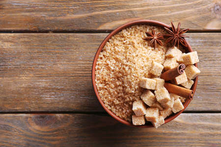 Brown sugar cubes and crystal sugar in bowl on wooden backgroundの写真素材
