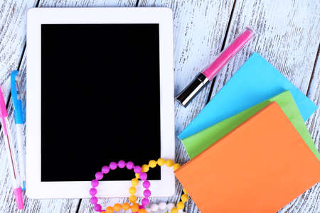 Tablet, bracelet, notebook and pen on wooden backgroundの写真素材