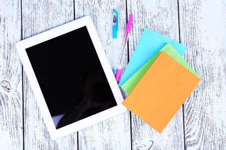 Tablet, notebook and pens on wooden backgroundの写真素材
