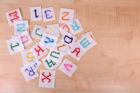 Handmade embroidered letters on white fabric, on wooden backgroundの写真素材