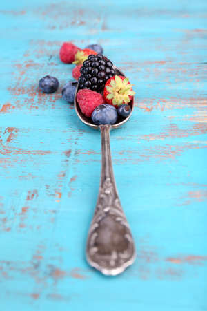 Ripe sweet different berries in vintage spoon, on old wooden tableの写真素材