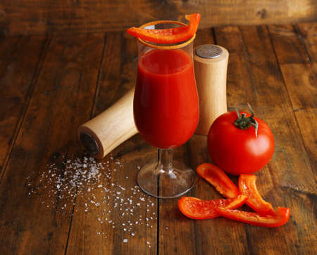 glass of tasty tomato juice and pepper on wooden tableの写真素材