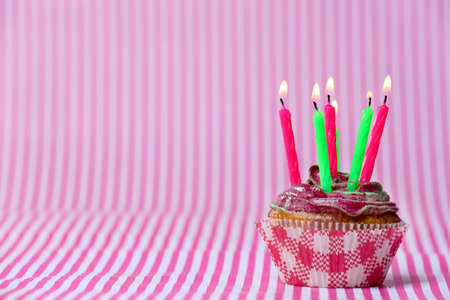 Delicious birthday cupcake on pink backgroundの写真素材
