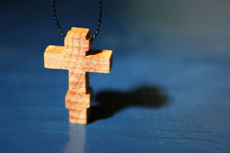 Wooden cross with deep shadow on wooden backgroundの写真素材