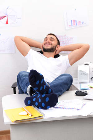 Confident businessman holding his legs in funny socks on deskの写真素材