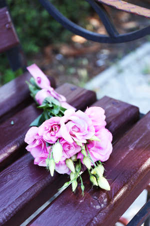 Beautiful bouquet of eustoma flowers on wooden bench in parkの写真素材