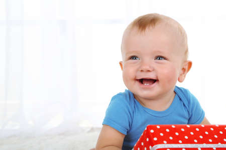 Cute baby boy with present box on carpet in roomの写真素材