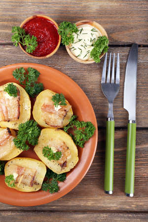 Baked potato with bacon on plate, on wooden backgroundの写真素材
