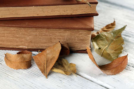 Books and dry leaves on wooden backgroundの写真素材