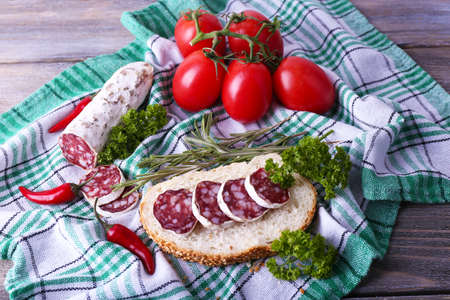 French salami with bread, tomatoes and parsley on fabric backgroundの写真素材