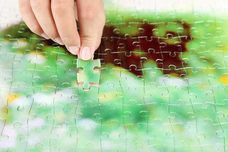 Hand holding puzzle piece on wooden table の写真素材