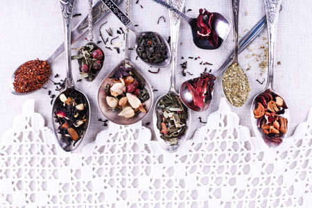 Tea in metal spoons on lace fabric backgroundの写真素材