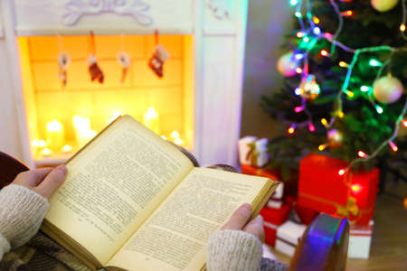 Woman holding book in front of fireplaceの写真素材