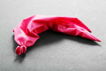 Popped pink balloon on paper backgroundの写真素材