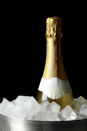 Bottle of champagne in bucket with ice, on black backgroundの写真素材