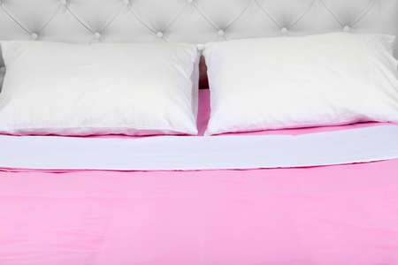 Bed in pink bed linen in roomの写真素材