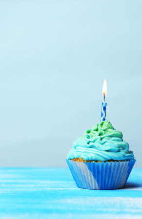 Delicious birthday cupcake on table on light blue backgroundの写真素材