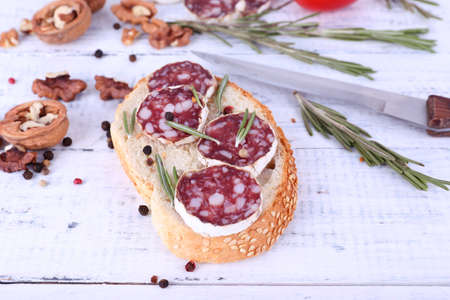 Sandwich with salami, rosemary and walnuts on wooden backgroundの写真素材