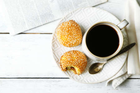 Cup of coffee with tasty cookie on color wooden の写真素材