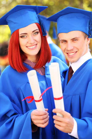 Graduate students wearing graduation hat and gown, outdoorsの写真素材