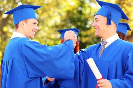 Graduate students wearing graduation hat and gown, outdoorsの写真素材