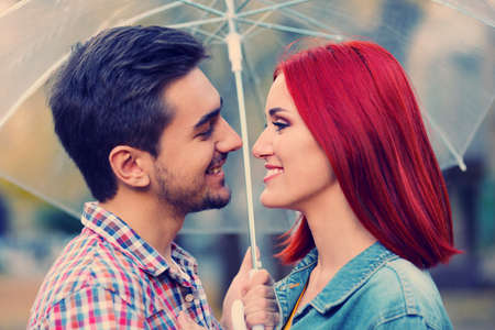 Loving couple under an umbrella in autumn parkの写真素材