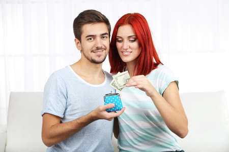 Loving couple sitting in sofa with purse in roomの写真素材